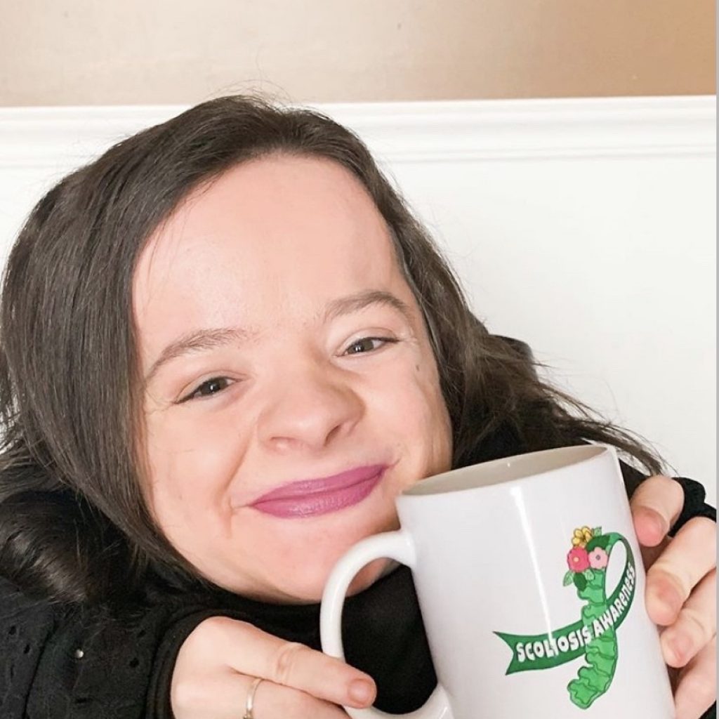 Michaela Davert smiling with scoliosis awareness mug