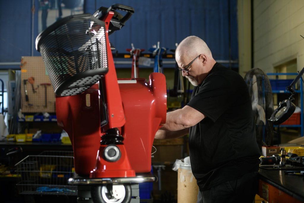 Production employee building an Amigo scooter.