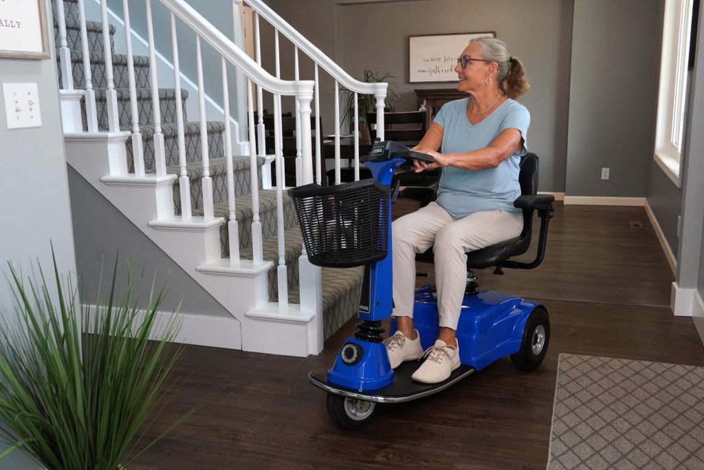 Woman seated on an Amigo scooter driving through her house.