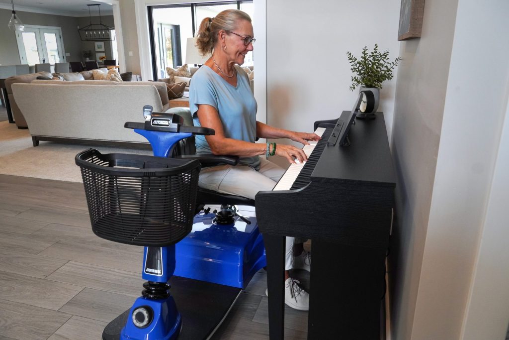 Woman seated on an Amigo scooter while playing piano.